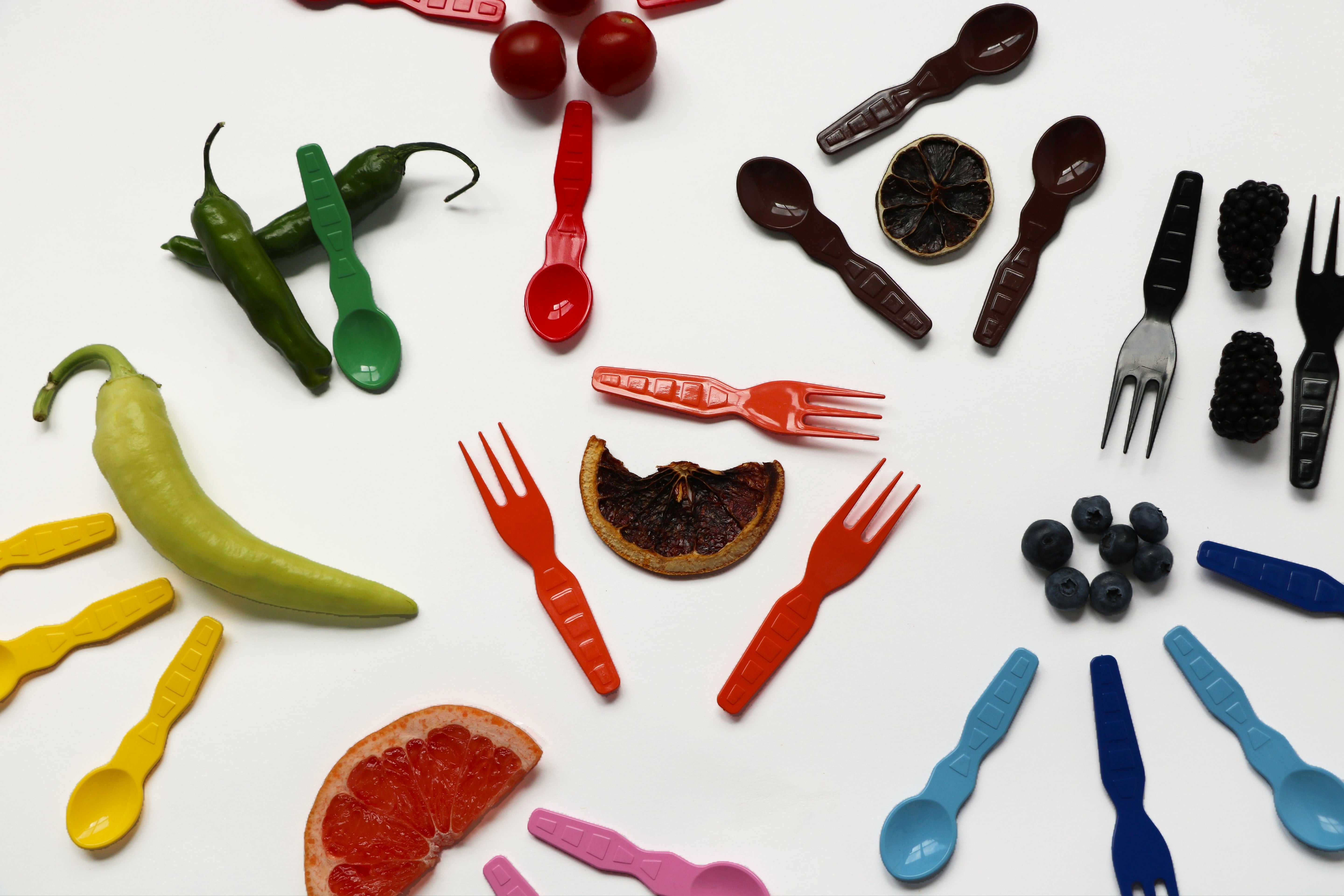 Compostable tasting spoons made from plant-based PLA, each holding a bite-sized appetizer with fried chicken, celery, blue cheese, and a decorative skewer, arranged on a catering tray.